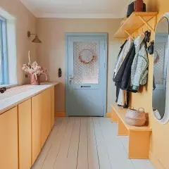 Warme Farben und natürliche Materialien prägen diesen Flur. Farbgestaltung Flur Tapeten Beispiele: Gelbe Schränke, Holzboden, Garderobe mit Jacken.