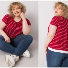 Kobieta plus size w czerwonej bluzce w paski i jeansach siedzi na podłodze.