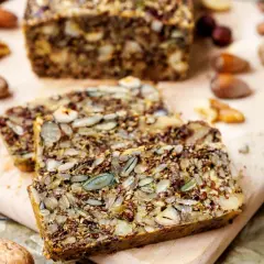 Ein rustikales Keto Brot Rezept mit vielen Kernen und Nüssen, auf einem Holzbrett serviert.