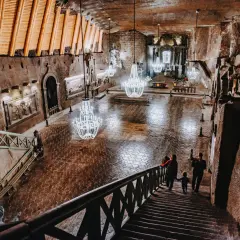Rodzina schodzi schodami do podziemnej kaplicy w kopalni soli „wieliczka” opinie. Kryształowe żyrandole oświetlają solne rzeźby.