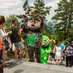 Maskotki w solina park rozrywki witają gości. Wesołe postacie w otoczeniu zieleni i drzew.