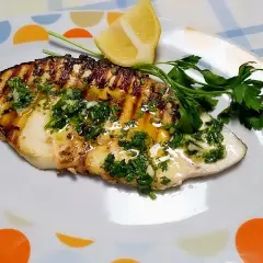 Filete de pez espada a la parrilla con perejil picado y limón.