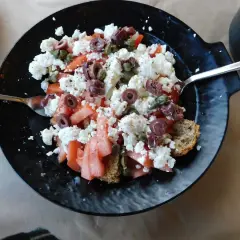 Grecka sałatka Dakos z fetą, pomidorami, oliwkami i kaparami na chlebie.
