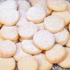 Stos pysznych, okrągłych ciastek niemieckich, oprószonych cukrem pudrem. Idealne na święta!