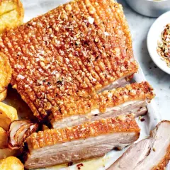 Poitrine de porc croustillante, servie avec des pommes de terre rôties et des oignons caramélisés. Un délice pour les papilles !