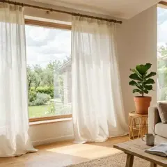 Tende leggere che arrivano fino al soffitto, creando un'atmosfera ariosa e luminosa in un soggiorno accogliente con vista sul giardino.