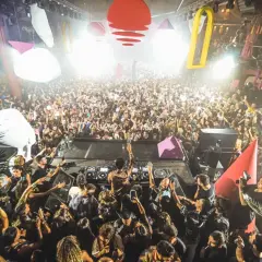 Una folla immensa balla al ritmo di una **canzone ibiza** in un locale notturno. Luci stroboscopiche e decorazioni colorate creano un'atmosfera elettrizzante.