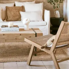 Gemütliches Wohnzimmer im boheme stil mit Rattan-Stuhl, Holztisch und Kissen.