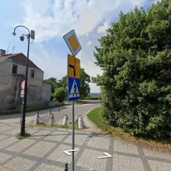 Znak pierwszeństwo łamane kierunkowskaz informuje o skręcie w prawo i ustąpieniu pierwszeństwa. Obok znak przejścia dla pieszych.