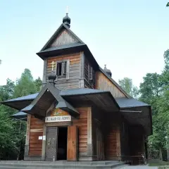 Drewniana cerkiew otoczona lasem, idealne miejsce na grabarka zwiedzanie. Wokół widać krzyże pielgrzymkowe.