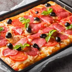 Szybka pizza z salami, pomidorami i oliwkami, udekorowana listkami bazylii, wprost z blachy. Idealna na szybki głód!