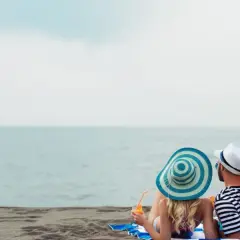 Para relaksu na plaży w Mielnie. Para w kapeluszach popija drinki, ciesząc się widokiem morza. Idealne mielno atrakcje dla dorosłych.