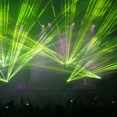 Koncertowe szaleństwo! Zielone lasery rozświetlają scenę, tworząc niesamowitą atmosferę dla zagranicznych legendarnych zespołów rockowych. Tłum szaleje.