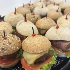 Mini hamburgery gdzie kupić? Taca pełna pysznych, małych burgerów z serem, warzywami i różnymi bułkami. Idealne na imprezę!