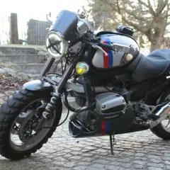 Zmodyfikowany BMW R 1100 R z okrągłym reflektorem i ozdobnymi pasami w barwach narodowych, gotowy na przygodę.