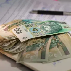 Stos banknotów 100 zł leży na dokumentach. Może to być związane z oceną stopnie niepełnosprawności i przyznawanymi świadczeniami.
