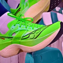 Jaskrawozielone buty biegowe Saucony, znanej firmy z USA, gotowe do bicia rekordów na stadionie.