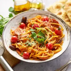 Pyszny makaron z chorizo, pomidorkami koktajlowymi i świeżą bazylią, posypany parmezanem. Obok focaccia i oliwa.