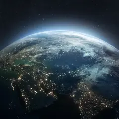 Widok Ziemi z kosmosu nocą, rozświetlonej miastami. W tle gwiazdy i delikatna poświata atmosfery, jakby patrzyły na nią satelity.