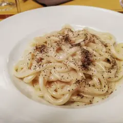Piatto di pici cacio e pepe, pasta fatta a mano condita con pecorino romano e pepe nero macinato fresco.