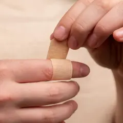 Dłoń zakłada plaster na palec. Czy ziarnina jest niebezpieczna? Pielęgnacja rany jest ważna.