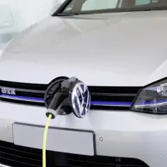 Une Golf 7 GTE blanche est branchée à une borne de recharge. Le câble jaune est visible.