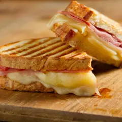 Dos deliciosos panini de queso con jamón, el queso derretido se desborda.