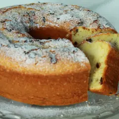 Un soffice ciambellone allo yogurt, cosparso di zucchero a velo e gocce di cioccolato, pronto per essere gustato.