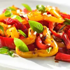 Peperoni al forno colorati, dolci e succosi, guarniti con basilico fresco e aglio. Un contorno estivo perfetto.