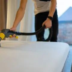 Persona usando un limpiador de tapicería para mostrar como limpiar un colchón muy sucio.