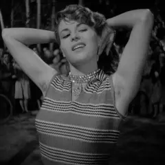 Una donna con le braccia alzate, un sorriso sulle labbra e un'espressione che evoca il "riso amaro significato". Sullo sfondo, una folla indistinta.