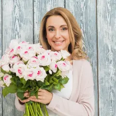 Uśmiechnięta blondynka z bukietem jasnoróżowych róż, gotowa na imieniny Justyny.