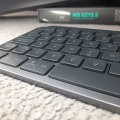 Szara klawiatura Logitech MX Keys S na puszystym dywanie. Klawisz "Enter" jest twardy i gotowy do akcji.