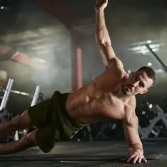 Mann trainiert seine **abs muskeln** in einem Fitnessstudio. Er macht eine seitliche Plank-Übung, wobei sein Körper gerade und angespannt ist.