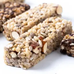 Kilka batonów proteinowych z orzechami, nasionami i czekoladą na białym tle.