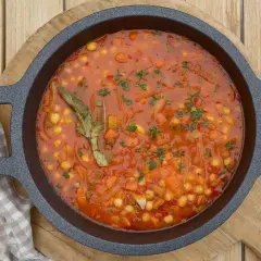 Un plato humeante de garbanzos con verduras, lleno de zanahoria, cebolla y especias, listo para ser disfrutado.