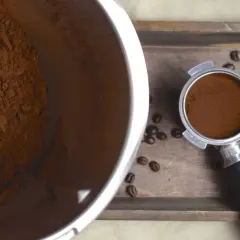 Frisch gemahlene Kaffeebohnen im Thermomix-Behälter und im Siebträger. Der Duft von frisch gemahlenem Kaffee liegt in der Luft.