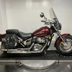 Motocicleta Suzuki Marauder 800 roja con alforjas de cuero y parabrisas.