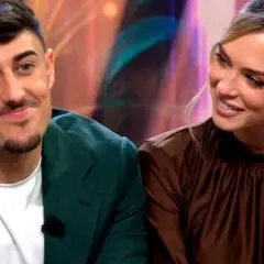 Almudena y Borja, sonriendo y mirando hacia un lado. Él lleva una chaqueta verde y ella un vestido marrón.