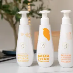 Emolienty co to? Trzy białe butelki z pompką: emulsja myjąca, balsam dermo i balsam kojący dla dzieci.