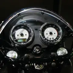 Klasyczny przebieg motocykla: prędkościomierz i obrotomierz w chromowanych obudowach, podświetlane kontrolki i kluczyk zapłonu.