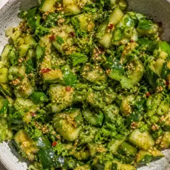 En skål med pressgurka snabb, toppad med färska örter och sesamfrön. En fräsch och smakrik rätt.