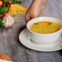 En skål med klar buljong med små nudlar, morötter och persilja. En fråga om hur man får bort salt smak kan uppstå om buljongen är för salt.
