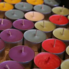 Un surtido de velas no tóxicas de colores vibrantes, dispuestas en filas.