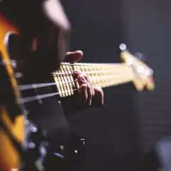 Main d'un bassiste jouant sur une guitare électrique. Parfait pour un texte pour annoncer la sortie d'un single.