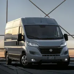 Szary Fiat Ducato na tle zachodzącego słońca. Zastanawiasz się nad pojemnością baku? Ten model oferuje duży zasięg.