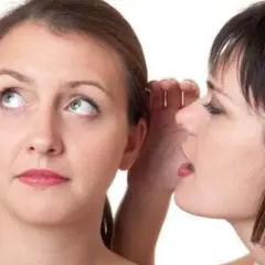Two women, one whispering into the other's ear.
