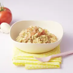 Un bol d'omelette bébé aux tomates et pommes de terre, avec des ingrédients frais à côté.