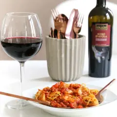 Ein Glas Rotwein und eine Portion Spaghetti Bolognese mit einem Hauch von Rotwein. Perfekt für einen gemütlichen Abend.