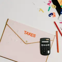 Kalkulator, koperta z napisem TAXES, pisaki i luźne cyfry, jakby ktoś próbował ustalić numer NIP.